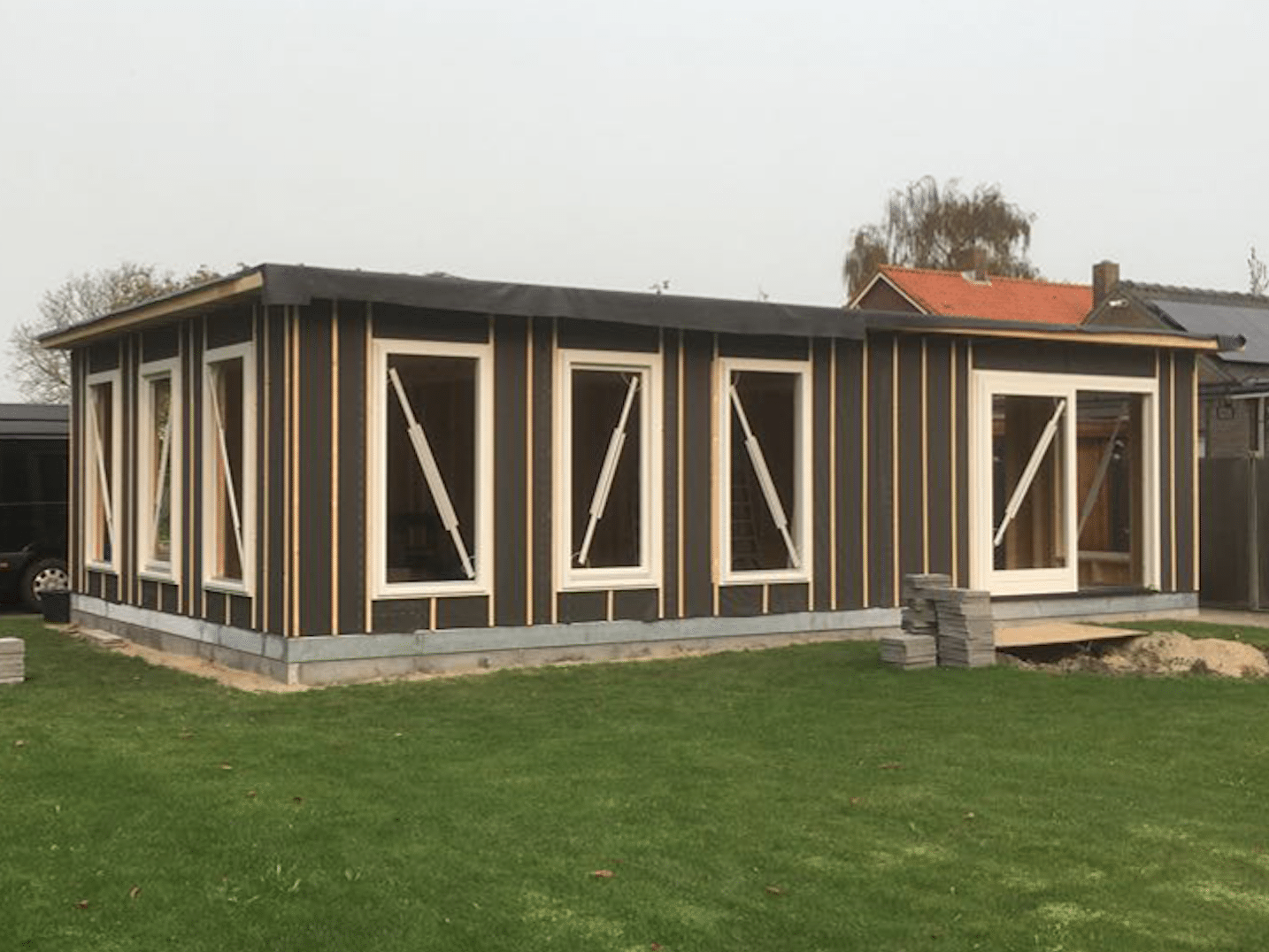 Overzicht van geplaatste witte kunststof kozijnen in zwarte houtskeletbouw buitengevel – Toelevering Online