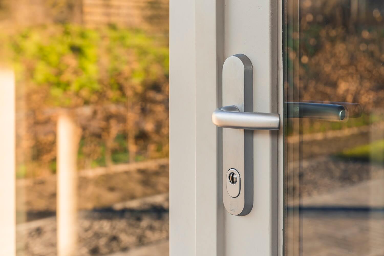 Close-up van SKG-gecertificeerd veiligheidsschild met kruk en cilinderslot op witte buitendeur – Toelevering Online