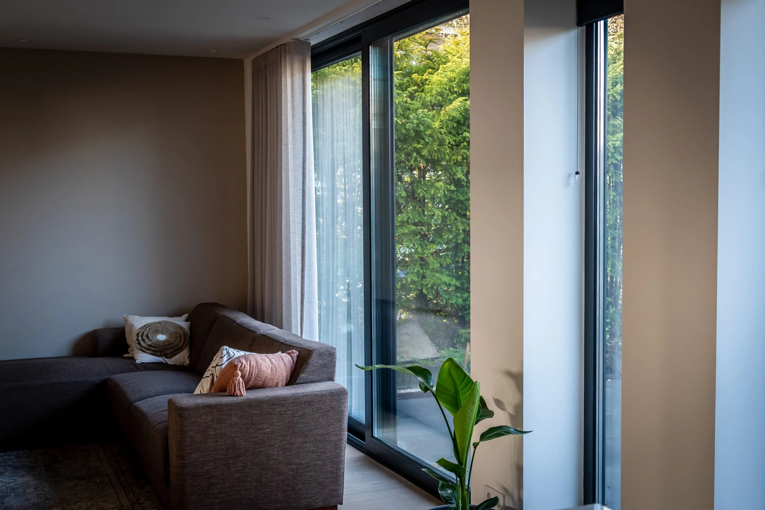 Binnenhoek van woonkamer met aluminium Reynaers CP130 schuifpui en strakke afwerking tot plafond – Toelevering Online